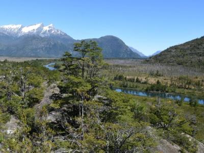 Scenic view of a river winding through a valley with snow-capped mountains in Cochrane, Chilean Patagonia.