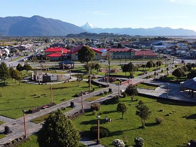 Panoramic view of Chaitén from above, showcasing the park, buildings, and mountain range.